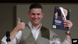 FILE - Richard Spencer, who leads a movement that mixes racism, white nationalism and populism, holds up a magazine cover showing President-elect Donald Trump before signing it for a supporter in College Station, Texas, Dec. 6, 2016.