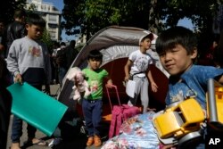 FILE - Migrant children carrying toys and bags leave from their family's tent at Victoria square in Athens, Oct. 1, 2015. Aid agencies are warning that a whole generation of Syrian children is being mentally scarred by the conflict at home – and by the difficulties of life as a refugee.