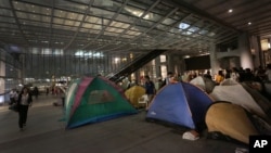 People walk past protesters' tents outside the HSBC headquarters in Hong Kong, August. 27, 2012.