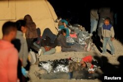 A young boy walks near other migrants lying on the ground inside an enclosure, where they are being held by U.S. Customs and Border Protection, after crossing the U.S.-Mexico border illegally and turning themselves in to request asylum, in El Paso, Texas, March 29, 2019.