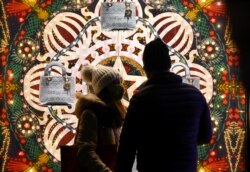 People wearing a face mask do some window shopping on Piazza di Spagna in central Rome on December 13, 2020, during the COVID-19 pandemic caused by the novel coronavirus. (Photo by Vincenzo PINTO / AFP)