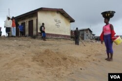 Seen in the background is the only public toilet in West Point, Monrovia, Liberia, Sept. 25, 2014. (Benno Muchler /VOA)