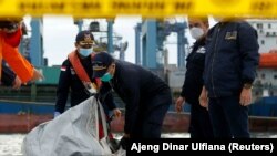 Anggota penyelamat membawa serpihan pesawat Sriwijaya Air penerbangan SJ182 yang jatuh ke laut, di pelabuhan Terminal Kontainer Internasional Jakarta, 10 Januari 2021. (Foto: REUTERS/Ajeng Dinar Ulfiana)