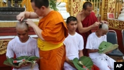 Soccer coach Ekkapol Chantawong, left, and teammates who were rescued last week from a flooded cave have their heads shaved in a traditional Buddhist ceremony in Mae Sai district, Chiang Rai province, northern Thailand, Tuesday, July 24, 2018. (AP Photo/Sakchai Lalit)