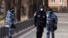 FILE - Police officers wearing face masks patrol at Patriarch Ponds in Moscow, Russia, April 22, 2020.