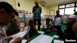 Election commission official Dedi Saidi, left, reads document stating the number of votes collected in ballot boxes, Bendungan Hilir, Jakarta, July 10, 2014.