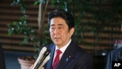 Japan's Prime Minister Shinzo Abe, center, speaks to reporters at his official residence in Tokyo, July 17, 2015. 
