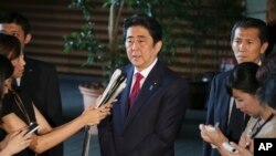 FILE - Japan's Prime Minister Shinzo Abe, center, speaks to reporters at his official residence in Tokyo, July 17, 2015. 
