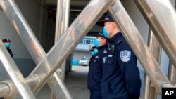 FILE - Security officers stand in formation near a court building in Dandong in northeastern China's Liaoning province, March 19, 2021. 