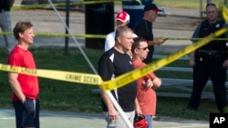 Members of the Republican Congressional softball team stand behind police tape in Alexandria, Va., Wednesday, June 14, 2017, after a multiple shooting involving House Majority Whip Steve Scalise of La. during a Congressional baseball practice. (AP Photo/Cliff Owen)