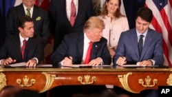 President Trump, looks over at Canada's Prime Minister Justin Trudeau's document as they and Mexico's President Enrique Pena Nieto sign a new United States-Mexico-Canada Agreement that replaces the NAFTA trade deal, at a hotel before the start of the G20 