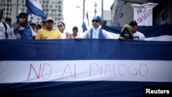 Nicaraguans display a national flag saying "No to dialogue" during a protest in San Jose, Costa Rica, against the talks their President Daniel Ortega will resume with the leaders of the opposition, Feb. 22, 2019.