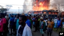 Warga Papua berkumpul di dekat toko yang terbakar dalam aksi protes di Wamena, provinsi Papua, 23 September 2019. 