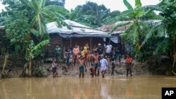 Rohingya refugees look at floodwater following heavy rains at the Rohingya refugee camp in Kutupalong, Bangladesh, July 28, 2021.