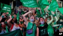 Aktivis hak-hak aborsi menonton streaming video langsung dari anggota parlemen dalam sesi, di luar Kongres di Buenos Aires, Argentina, Rabu, 30 Desember 2020. Kongres menyetujui undang-undang yang melegalkan aborsi di Argentina. (Foto: AP/Natacha Pisarenko)