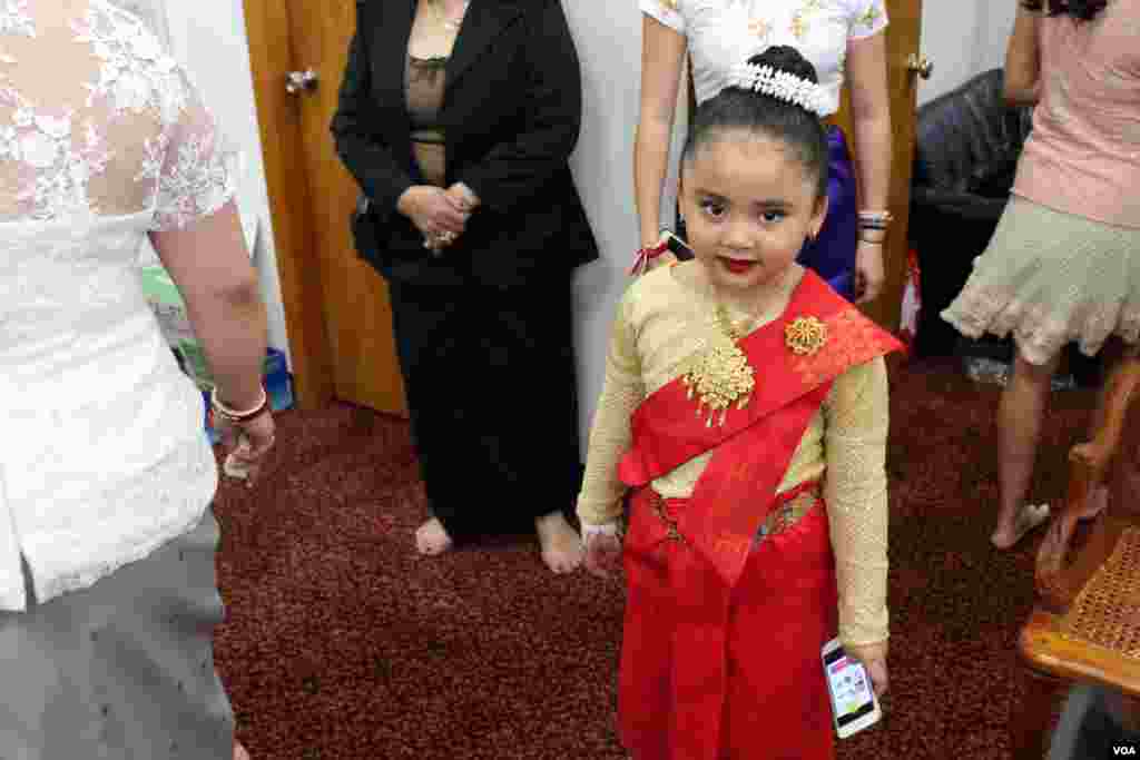 អ្នក​រាំ​របាំ​តូច​ម្នាក់​សម្រាក​ហើយ​លេង​ទូរស័ព្ទ​របស់​នាង។ (ចាប ចិត្រា/VOA)