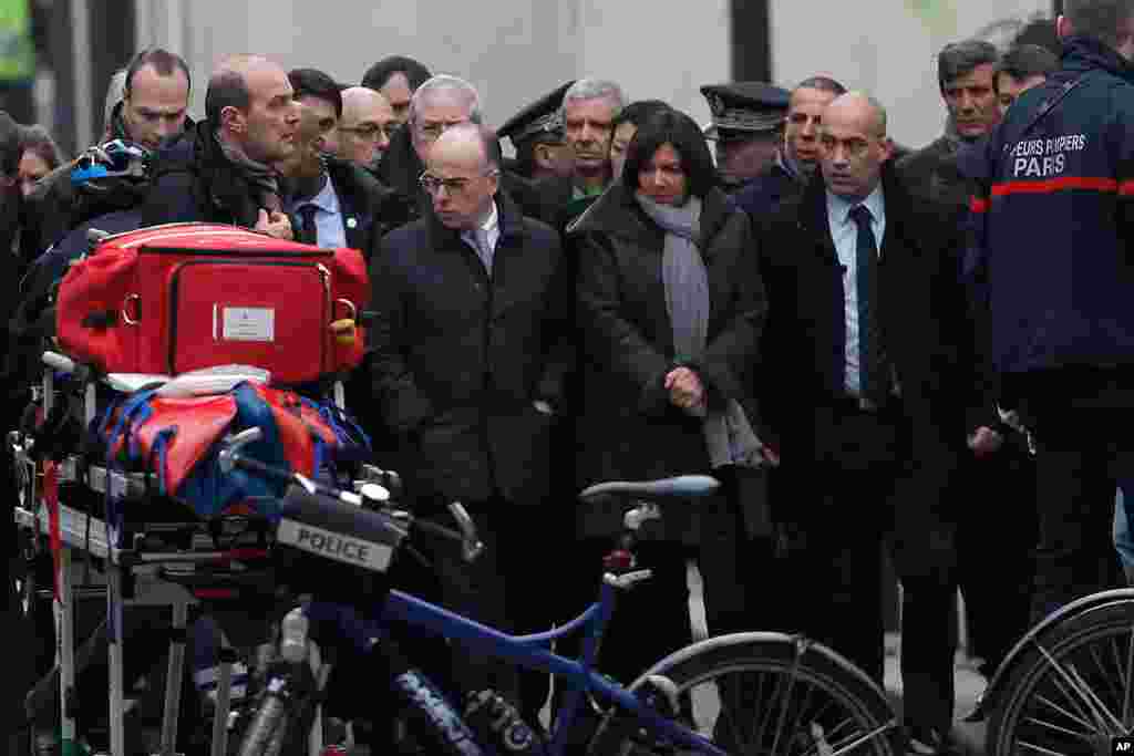 Menteri Dalam Negeri Perancis Bernard Cazeneuve (tengah, kiri) dan walikota Paris, Anne Hidalgo (tengah, kanan) tiba di kantor tabloid satiris Perancis Charlie Hebdo di&nbsp;Paris (7/1).