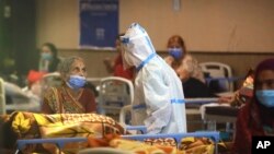 Seorang petugas tengah berbicara dengan pasien di tempat karantina khusus pasien COVID-19 di New Delhi, India, 19 April 2021. (AP Photo/Manish Swarup)