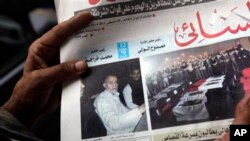 An Egyptian in Cairo holds the Al-Ahram newspaper fronted by a picture of Mohammed Badie, the supreme leader of the Muslim Brotherhood, left, and pictures of flag-draped coffins containing the bodies of slain off-duty policemen, Aug. 20, 2013.