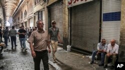 Orang-orang berjalan di Bazar Besar melewati toko-toko yang tutup menyusul unjuk rasa di Tehran, Iran, Senin, 25 Juni 2018.