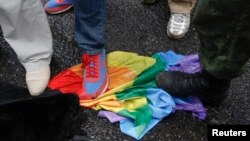 Anti-gay rights activists stand on a rainbow flag during a protest by gay rights activists who oppose a proposed new law termed by the State Duma as "against advocating the rejection of traditional family values," Moscow, June 11, 2013.