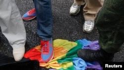 FILE - Anti-gay rights activists stand on a rainbow flag during a protest by gay rights activists demonstrating against a proposed new law termed by the State Duma, the lower house of Parliament, as "against advocating the rejection of traditional family values" in central Moscow, June 11, 2013. 