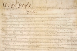 This photo made available by the U.S. National Archives shows a portion of the first page of the United States Constitution.