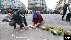 Les gens laissent des bougies et des fleurs en hommage aux victimes des attentats à la bombe en face de l'immeuble de la bourse dans le centre -ville de Bruxelles le 22 Mars, ici 2016.