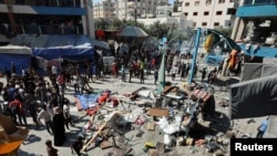 Palestinians gather at the site of an Israeli air strike on a UN school sheltering displaced people, amid the Israel-Hamas conflict, in Nusairat in central Gaza Strip, July 14, 2024. 
