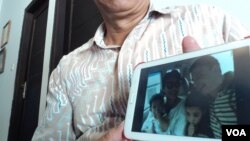 Seorang kerabat memperlihatkan foto keluarga Yuli Hastini, yang merupakan penumpang pesawat Malaysia Airlines MH17 yang jatuh di Ukraina. (VOA/Yudha Satriawan)