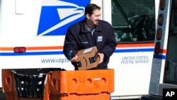 যুক্তরাষ্ট্রের একজন ডাক কর্মচারী ইলিনয়ে একটি পোস্ট অফিসের বাইরে পার্সেল লোড করছেন। ২৯ জানুয়ারি, ২০২৪।