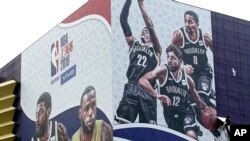 A worker takes down a billboard advertising an NBA preseason basketball game on Thursday between the Los Angeles Lakers and Brooklyn Nets in Shanghai, China, Wednesday, Oct. 9, 2019. The NBA has postponed Wednesday's scheduled media sessions in Shanghai…