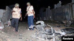 Somali police officers assess the scene of an explosion outside the Jazira hotel in Mogadishu, Jan. 1, 2014. 