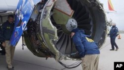 In this April 17, 2018 frame from video, a National Transportation Safety Board investigator examines damage to the engine of the Southwest Airlines plane that made an emergency landing at Philadelphia International Airport in Philadelphia.