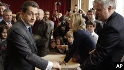 Presiden Perancis dan kandidat UMP Nicolas Sarkozy (kiri) memasukkan surat suaranya ke kotak di salah satu TPS di Paris (6/5).