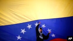 Seorang pemuda mengibarkan bendera Venezuela di tengah jalan ketika oposisi menyerukan jalan-jalan diblokir selama 10 jam di Caracas Venezuela, Senin, 10 Juli 2017.