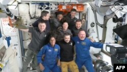 Potongan gambar dari video NASA yang menunjukkan astronaut Suni Williams (duduk, kiri) dan Butch Wilmore (duduk, kanan) berpose bersama kru Stasiun antariksa Internasional (ISS) setelah tiba di stasiun tersebut pada 6 Juni 2024. (Foto: Handout/NAS/AFP)