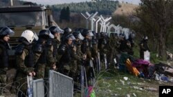 Macedonian policemen guard the borders of their country as an army truck arrives to build a border fence to prevent illegal crossings by migrants, in the Greek-Macedonian border near the Greek village of Idomeni, Nov. 28, 2015. 