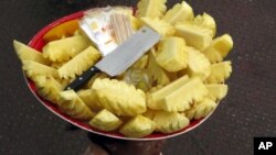 A vendor carries pieces of pineapple on her head during business at a jetty in Yangon, Myanmar, June 4, 2011.