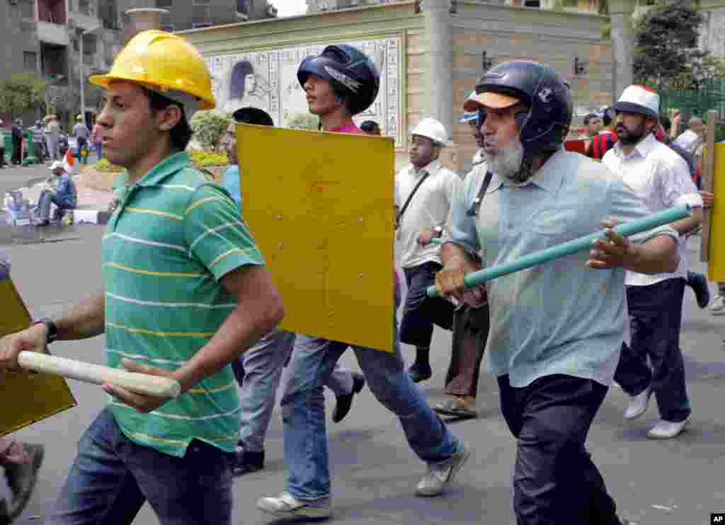Sayed Saafan, 57, right, an Egyptian supporter of Egypt&#39;s Islamist President Mohammed Morsi, holds a stick and wears protective gear during training outside of the Rabia el-Adawiya mosque near the presidential palace, July 2, 2013.