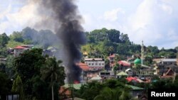 Asap mengepul dari gedung yang terbakar terlihat saat tentara pemerintah menyerang gerilyawan dari kelompok Maute, mengambil alih sebagian besar Kota Marawi, Filipina, 1 Juni 2017. (REUTERS/Romeo Ranoco)
