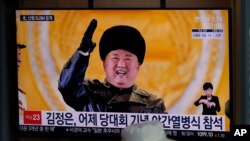 A man wearing a face mask sits in front of a TV screen showing North Korean leader Kim Jong Un, at the Seoul Railway Station in Seoul, South Korea, Jan. 15, 2021. 