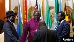 FILE - South Sudan's rebel leader Riek Machar (R) and South Sudan's President Salva Kiir (L) hold a priest's hands before signing an earlier peace agreement in Addis Ababa May 9, 2014.