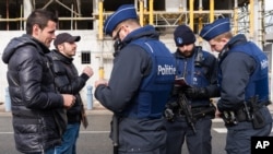 Des policiers vérifient l'identité de deux hommes qui ont tenté de traverser la frontière franco-belge à Adinkerke, en Belgique, le 24 février 2016.