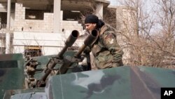 FILE - A Syrian army soldier stands on top of a gun-mounted vehicle in Salma, Syria, Jan. 22, 2016.