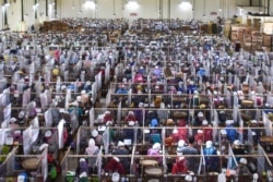 Buruh pabrik rokok tengah melinting tembakau di terminal kerja yang dipisahkan dengan penutup plastik sebagai tindakan pencegahan di tengah pandemi COVID-19, di pabrik rokok Gudang Baru, Malang, Jawa Timur, 11 Juli 2020. (Foto: AMAN ROCHMAN / AFP)