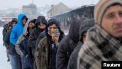 Migranti čekaju u redu kako bi primili besplatan tanjir hrane, na snegu, ispred napušenog skladišta Carine u Beogradu, Srbija, 20. januara 2017. (REUTERS/Marko Djurica - RTSW2DA)