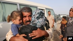 Askar Abdul Rahmon Ismoil Fallujadan qochishga muvaffaq bo'lgan oilasini bag'riga bosdi.