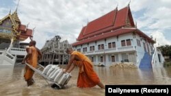 ព្រះសង្ឃ ទាញ​រទេះ​មួយ​ដែល​ដឹក​បាវ​ខ្សាច់ យក​ទៅ​ទប់​ការពារ​វត្ត​មួយ​ពី​ទឹកជំនន់​នៅ​ខេត្តអយុធ្យា ប្រទេសថៃ កាលពី​ថ្ងៃទី២៧ ខែកញ្ញា ឆ្នាំ២០២១។