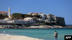 A man walks on the beach of Algajola on Feb. 18, 2017, on the French Mediterranean island of Corsica.